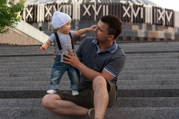 Father with one year old baby in his arms. Walk in an urban environment. The concept of urbanization and life in the city. The development of emotional intelligence. Early development.