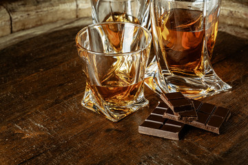 A bottle of cognac and glass on a brown wooden background. Brandy