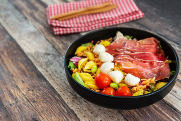 Salad made with cooked pasta, mixed green salads, cherry tomatoes, Mozzarella cheese and smoked ham served with accompaniment