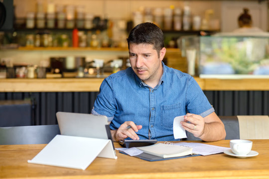 Mature new small business owner calculating online restaurant bill expenses and taxes