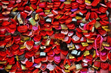 Locked locks of love and loyalty. Wall full of red and pink love locks shaped as hearts and...