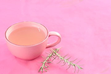 glass of rosemary tea on pink background