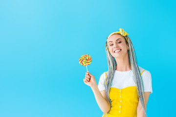 smiling girl with dreadlocks holding lollipop isolated on turquoise