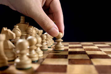 Male hand moving the white chess pawn during the game of chess
