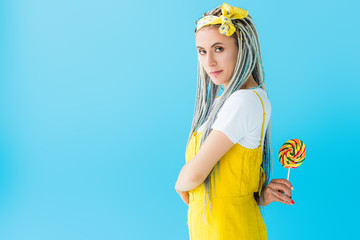girl with dreadlocks holding lollipop isolated on turquoise with copy space