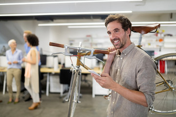 Happy coworker businessman carrying bicycle in modern office