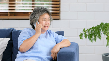 Senior asian woman talking phone while sitting in home livivg room, Asian old woman call phone with happiness, Senior, elderly, retired people and communication technology lifestyle - Powered by Adobe