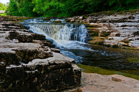 The fast flowing water of the River Ribble becomes blurred as it flows over Stainforth Force at Little Stainforth, Yorkshire.