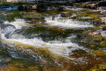 Fototapeta na wymiar The clear water of the River Ribble becomes a blur at Stainforth Force near Little Stainforth.