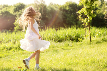 Fototapeta na wymiar Girl runs through the grass in a white dress