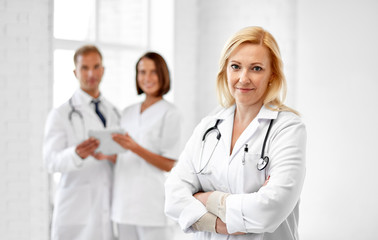 healthcare, medicine and profession concept - smiling female doctor in white coat at hospital