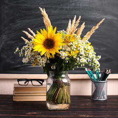 Teacher's day background. Black chalk board empty copy space and fresh wildflowers in vase. Holiday feminine poster.Spring greeting 8 march icon.