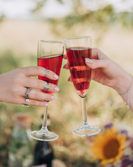two girls clink glasses with red champagne