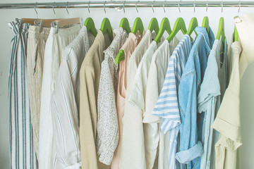summer wardrobe with linnen clothes on green hangers