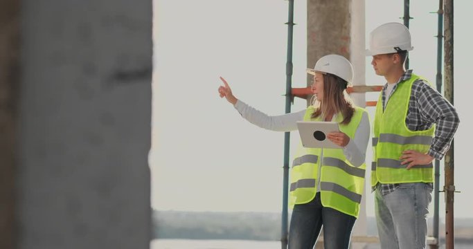 Engineers or architects have a discussion at construction site looking through the plan of construction. contre jour. Engineers or architects have a discussion.