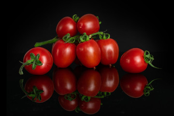 Lot of whole fresh red tomato cherry isolated on black glass