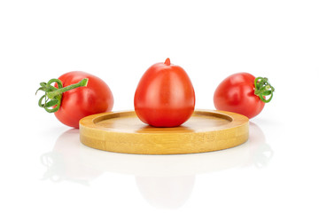 Group of three whole fresh red tomato cherry one on a bamboo plate isolated on white background