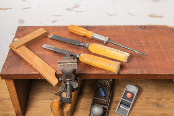 Old tools. Chisels, a screwdriver and a square are on the shelf. Planers on a wooden table