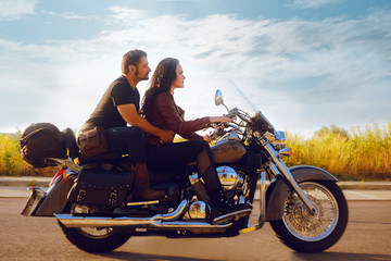 Fototapeta premium The girl rolls her boyfriend on a motorcycle. Girl is driving a motorcycle, the guy is sitting in the back