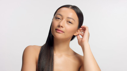 mixed race model touches her hair and watching to the camera, glowy natural ideal skin