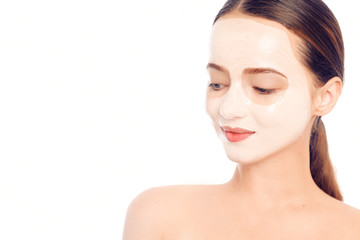 Brunette in a white mask for the face. Beautiful photo of a girl with perfect skin. A young girl cares for herself.