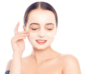 Brunette in a white mask for the face. Beautiful photo of a girl with perfect skin. A young girl cares for herself. Studio photo on a white background.