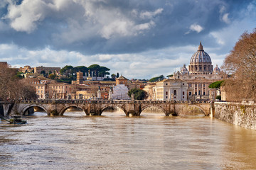 Fototapeta na wymiar St. Peter's cathedral and Tiber river with high water in February. Saint Peter Basilica in Vatican city with Saint Angelo Bridge in Rome, Italy