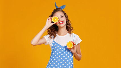cheerful young curly woman girl with   orange   on  yellow   background.cheerful young curly woman girl with   orange   on a yellow color background.