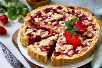 Delicious summer dessert strawberry pie with crumble, sweet delicious holiday cake with strawberry on a light stone or slate table.