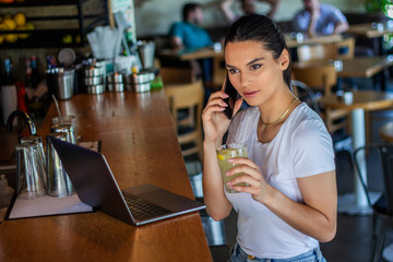 Young woman with coffee cup and laptop at coffe shop. Woman taking a break. Enjoying work from coffee shop. Doing Business From coffee shop