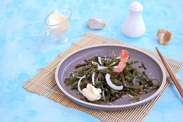 Light kelp, onion and shrimp salad on a brown clay plate. Served with mayonnaise sauce. Laminaria salad. Copy space.