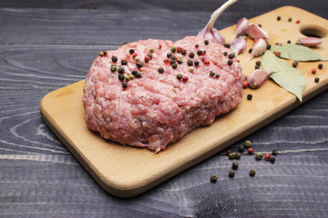 Burger. raw minced meat on cutting board with farlic and cpices onblack table top