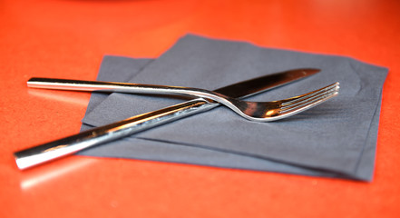 Before lunch. Fork and knife on gray napkin on red background