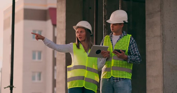 Engineers or architects have a discussion at construction site looking through the plan of construction. contre jour. Engineers or architects have a discussion.