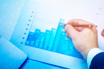 Magnifying glass and documents with analytics data lying on table, business finance background