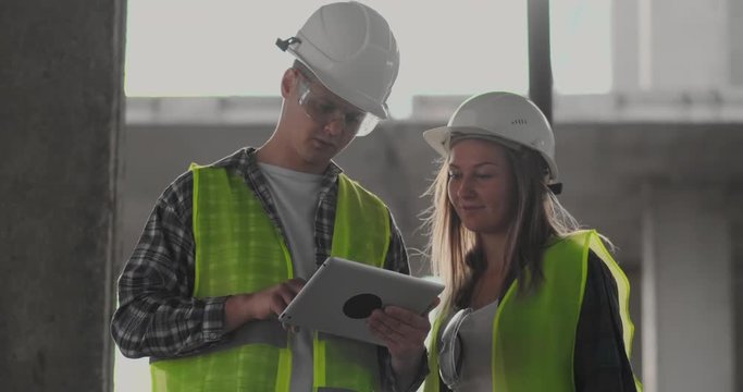 Construction site Team or architect and builder or worker with helmets discuss on a scaffold construction plan or blueprint or checklist.