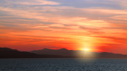 Orange sunset and mountains silhouette on Pacific Ocean. British Columbia. Canada 