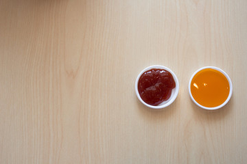 Chili sauce and tomato sauce on a small cup are placed in the middle and left and right. On the background on a wooden table