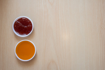 Chili sauce and tomato sauce on a small cup are placed in the middle and left and right. On the background on a wooden table
