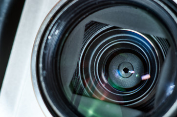 Close-up shot of compact camera (point and shoot) lens and aperture blades mechanism. Reflections, flares