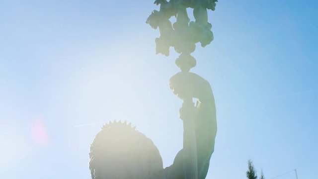 Close-up of statue of Neptune. Stock footage. Trident of statue of Poseidon rises against blue sky and is illuminated by bright sunlight. Statue of ancient Greek God of seas