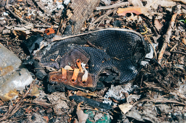 Old burnt shoe in forest garbage dump. Closeup shot