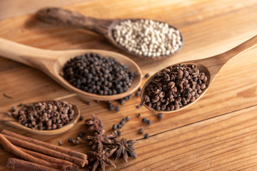 close up chille pepper in wooden spoon surround with spice powder on wooden table