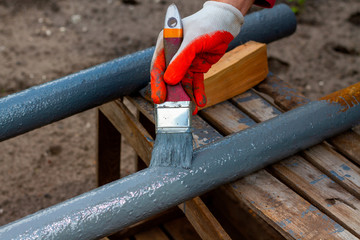 Paint rusty pipe gray protective paint. Male gloved hand paints a metallic rusty pipe. Paint work.