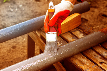 Paint rusty pipe gray protective paint. Male gloved hand paints a metallic rusty pipe. Paint work....