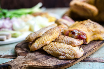 Pieces of fresh raw chicken parts on a cutting board on wooden old plank or table with blur Thai herbs and whole chicken. Chicken with Thai herbs prepared for cooking soup.