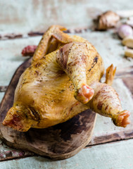 Whole fresh raw chicken on a cutting board on wooden old plank or table with blur Thai herbs and whole chicken. Chicken with Thai herbs prepared for cooking soup.
