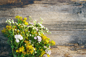 Bouquet of wild flowers on old wooden background, soft focus. Alternative medicine. White yarrow...