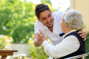Male nurse showing affection to old woman in garden.