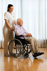 Senior man in wheelchair with nurse.